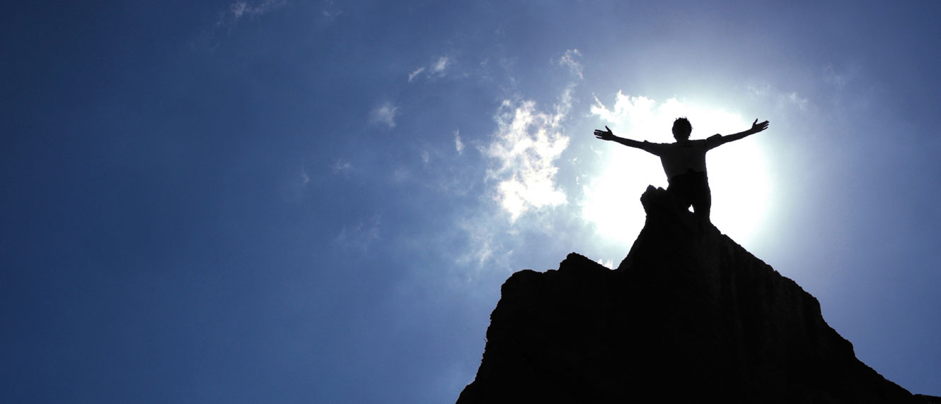 Silhouette of a climber on a mountain summit
